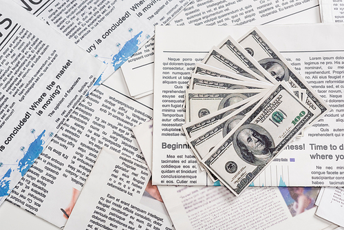 KYIV, UKRAINE - NOVEMBER 1, 2021: top view of dollar banknotes on printed newspapers