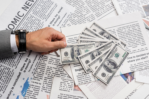 KYIV, UKRAINE - NOVEMBER 1, 2021: cropped view of man holding dollar banknote near printed newspapers