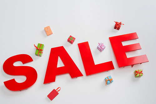 high angle view of sale letters near colorful small shopping bags and presents on white