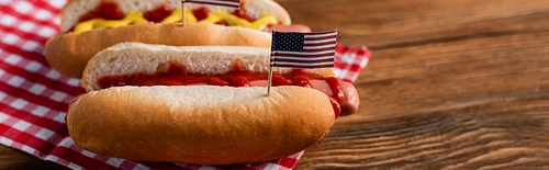 tasty hot fogs with small american flags on wooden table, banner