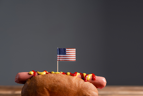 tasty hot dog with small american flag isolated on grey with copy space