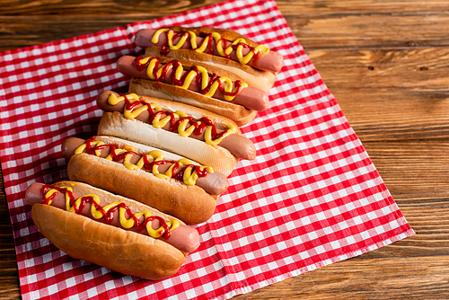 delicious hot dogs with ketchup and mustard, and plaid napkin on wooden table