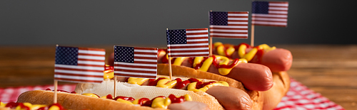 tasty hot dogs with ketchup, mustard and small usa flags isolated on grey, banner