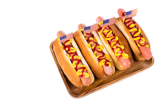 delicious hot dogs with small usa flags on wooden tray isolated on white