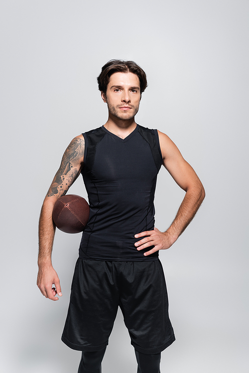 Tattooed sportsman with rugby ball  isolated on grey