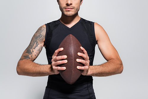 Cropped view of sportsman holding rugby ball isolated on grey