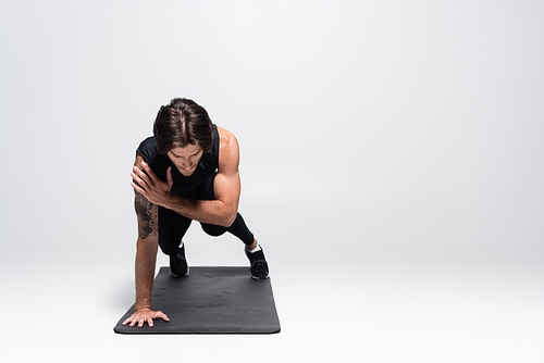 Athletic sportsman doing plank on one hand on grey background