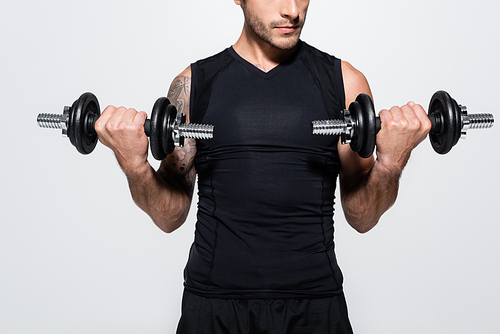 Cropped view of athletic sportsman training with dumbbells isolated on grey