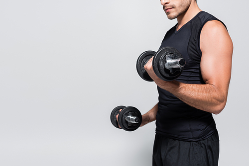 Cropped view of athletic sportsman working out with dumbbells isolated on grey