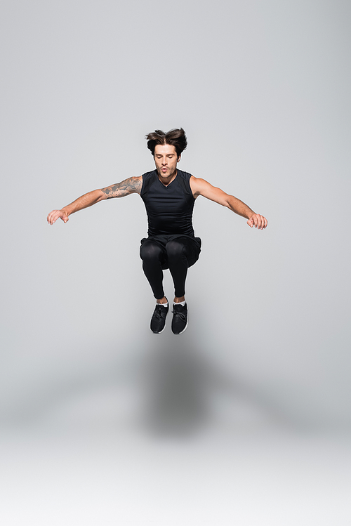 Brunette sportsman jumping on grey background