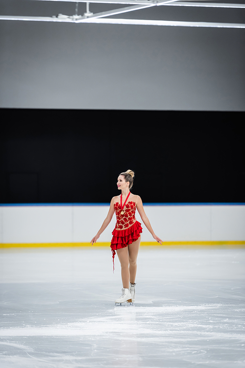 full length of happy young woman with medal figure skating in professional ice arena