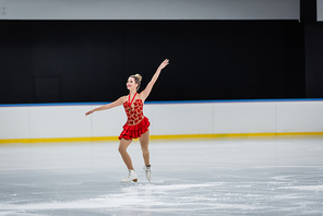 full length of cheerful woman with medal figure skating in professional ice arena