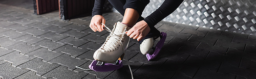 young woman tying laces on figure skating shoes, banner