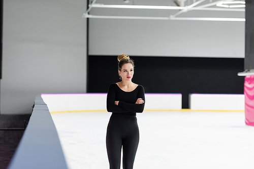 young figure skater in black bodysuit posing with crossed arms