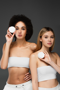 young multiethnic women  while holding body cream isolated on grey