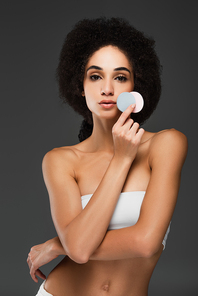 slim african american woman with perfect body and skin holding round cosmetic sponges isolated on grey