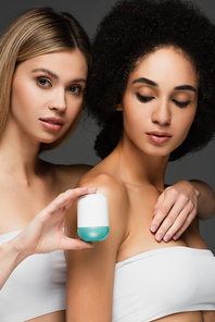 pretty interracial women with clean skin posing near antiperspirant isolated on grey