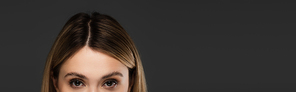 cropped view of young woman with natural makeup looking at camera isolated on grey, banner