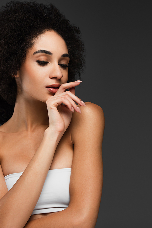 african american woman with perfect skin posing with hand near face isolated on grey