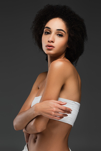 slim african american woman in white top looking at camera isolated on grey