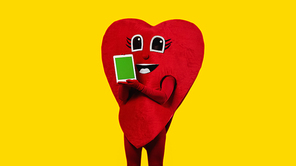 person in red heart costume holding digital tablet with green screen isolated on yellow