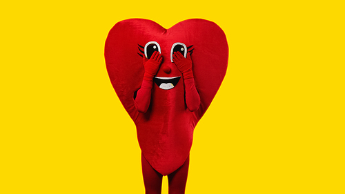 person in heart costume touching cartoon eyes isolated on yellow