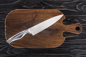 top view of wooden cutting board with knife on table