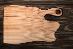 top view of wooden cutting board on brown table