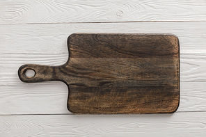 Top view of brown wooden cutting board on white surface