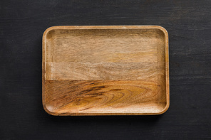 Top view of brown wooden empty dish on dark surface