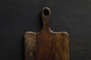 Top view of brown wooden cutting board on dark surface