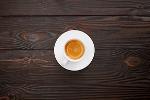 top view of cup of coffee with saucer on wooden surface