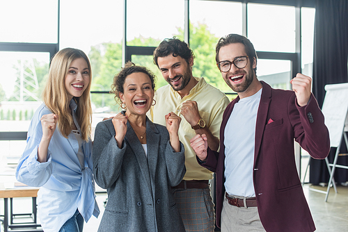 Excited interracial business people showing yes gesture at camera in office