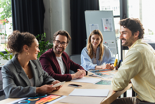 Business people smiling at african american colleague with calculator in office