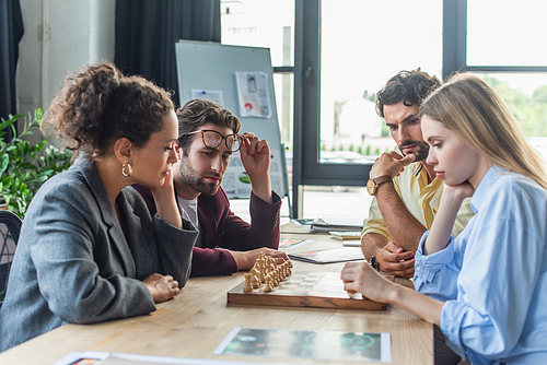 Multiethnic business people playing chess in office