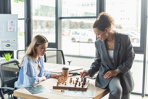 African american businesswoman playing chess with young colleague in office