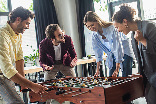Excited interracial business people playing table soccer in office