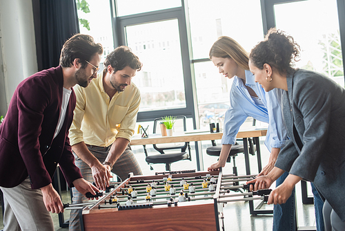 Multicultural business people playing table soccer together in office