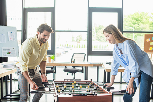 Businessman playing table soccer with young colleague in office