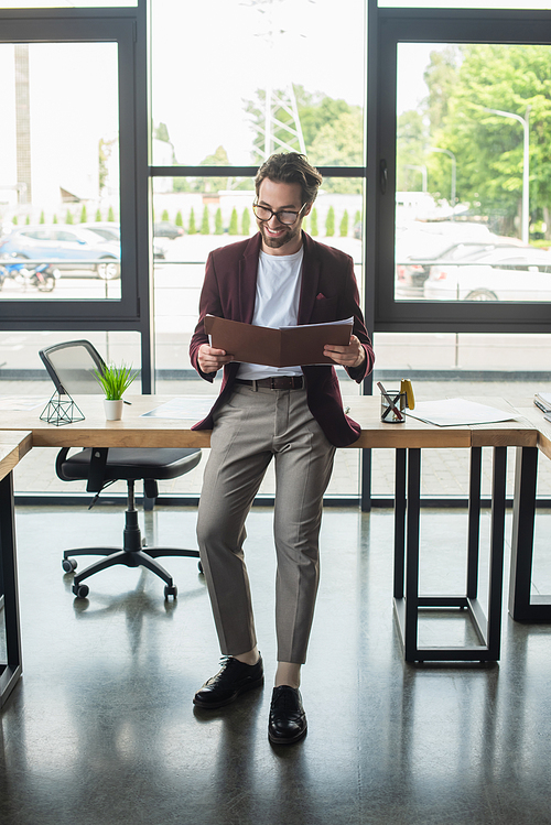 Businessman in formal wear looking at paper folder in office