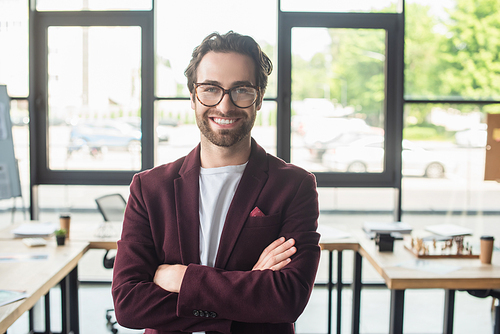 Young smiling businessman in eyeglasses  in blurred office