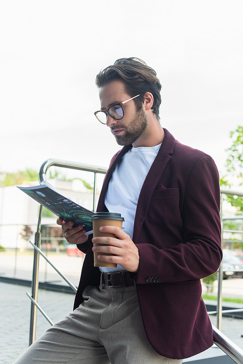 Businessman in formal wear and eyeglasses holding coffee to go and paper outdoors