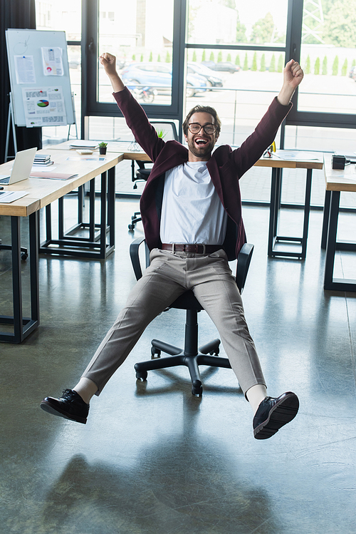 Excited businessman showing yes gesture on chair in office