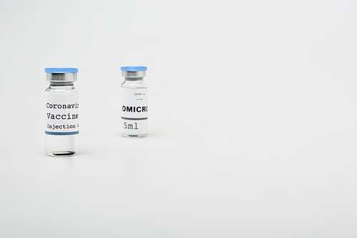 vials with covid-19 and omicron vaccine on grey background with copy space