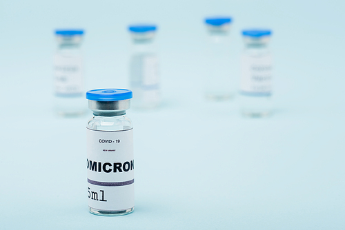 selective focus of covid-19 omicron variant vaccine near blurred vials on blue