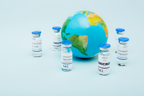 covid-19 omicron variant vaccine bottles near globe on blue background