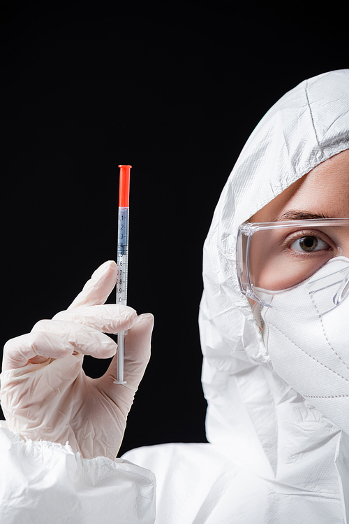 partial view of doctor in white hazmat suit holding syringe isolated on black