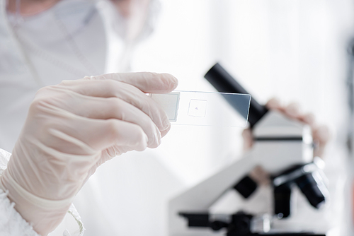 blurred scientist holding laboratory slide while working with microscope