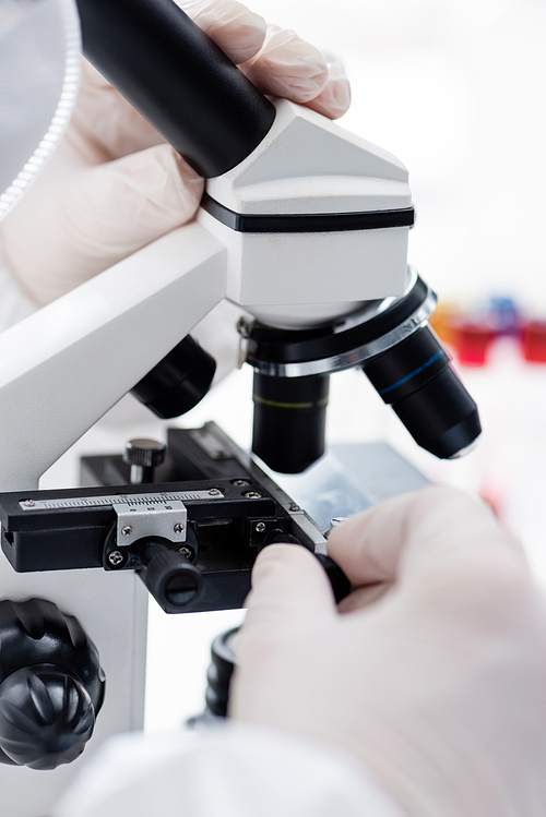 cropped view of biologist working with microscope in science laboratory, omicron variant concept