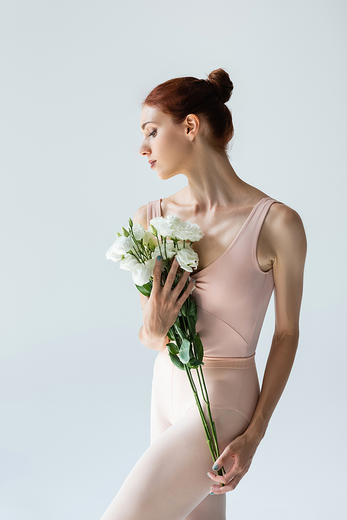 redhead ballerina holding bouquet of flowers isolated on grey